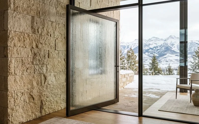 Custom textured glass pivot panel detail against a limestone wall